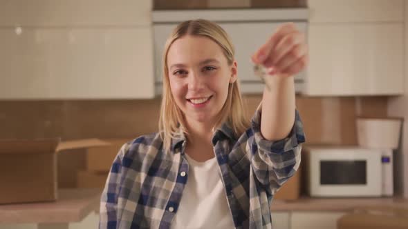 A Happy Young Woman in the Kitchen Holds the Keys to a New Apartment in Her Hand