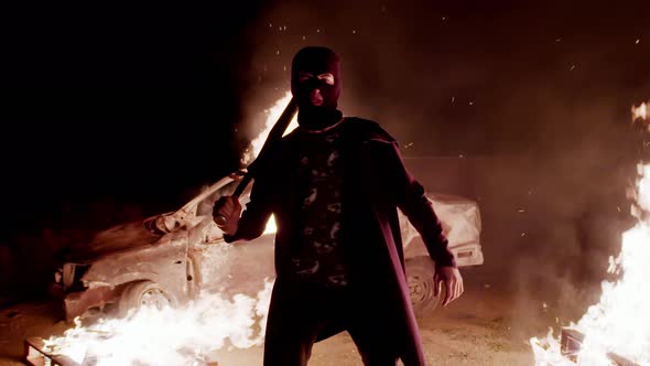 Thin Guy in Balaclava Helmet and Black Mantle Screams While Looking at Camera Against Background of alt