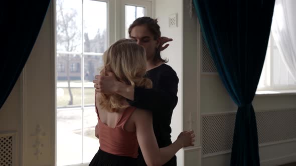 Young Blonde Woman and Her Boyfriend are Dancing and Embracing Natural Sunlight Indoors alt