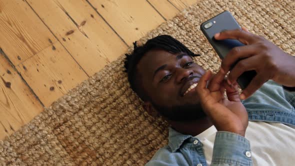 Man lying on the floor using smartphone alt