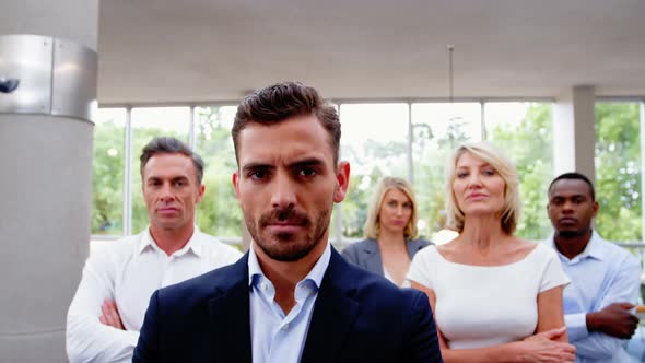 Business executives with arms crossed at conference center alt