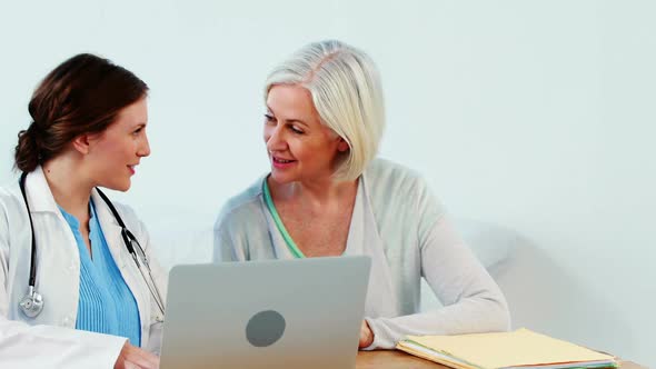 Female doctor interacting with a patient while using laptop alt