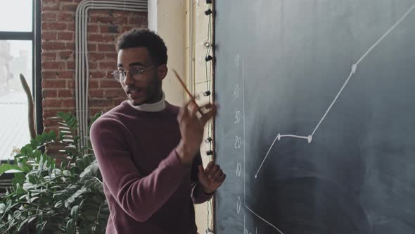 Man Explaining Graph on Blackboard alt