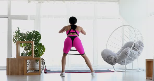 Beautiful black woman doing exercises using a fitness elastic band.