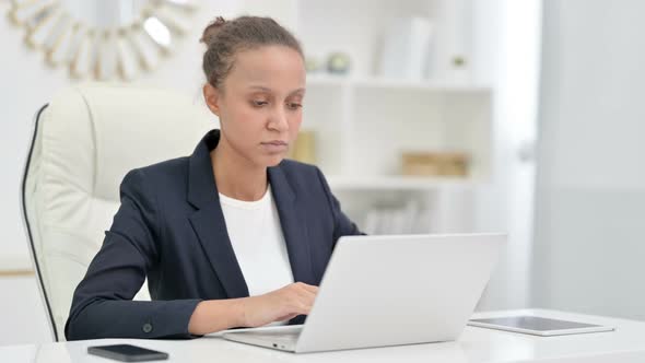 Focused African Businesswoman Working on Laptop in Office  alt