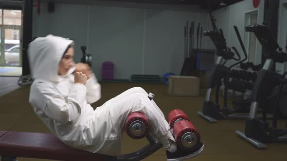 Muslim Woman Pumps Her Abdominal Muscles in a Fitness Center on Sports Simulators Lifting Her Body