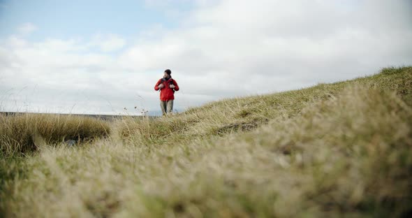 View of a Man Legs in Boots Walking on Green Moss and Grass in Iceland. alt