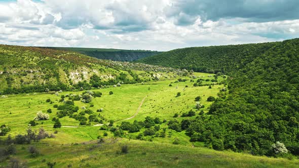 Aerial drone view of a valley in Moldova. River, a lot of greenery, cloudy sky alt