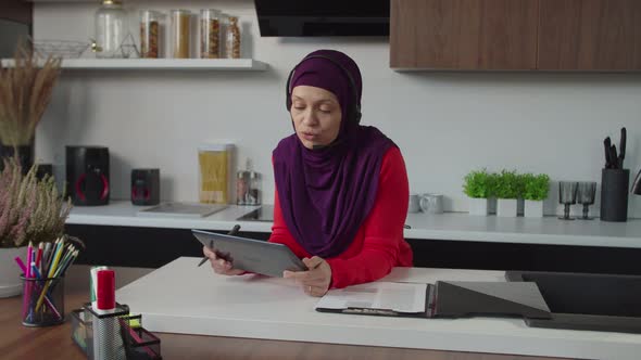 Successful Pretty Arab Businesswoman in Hijab with Headset Making Video Call on Tablet Pc Indoors alt