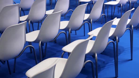 Empty White Chairs on a Blue Background in a Row