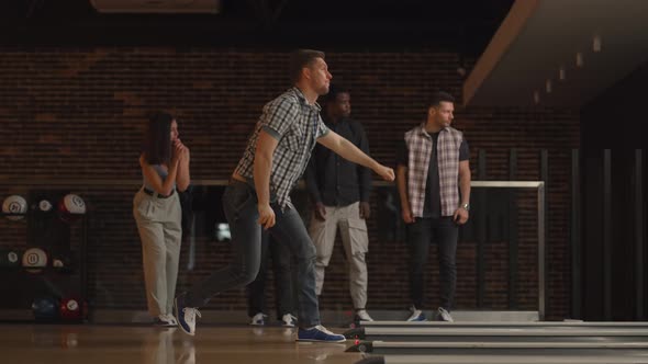 A Young Man Makes the Final Throw with a Bowling Ball and Wins the Game with the Support and Joy of alt