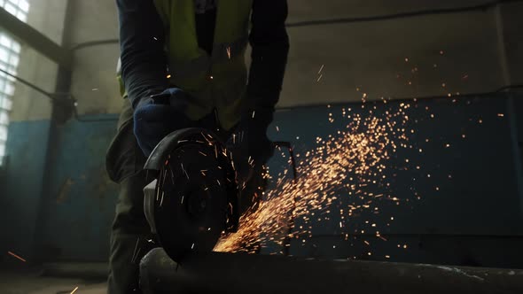 Close Up of Construction Worker Cuts Steel with a Circular Saw Construction Worker's Feet Flying alt