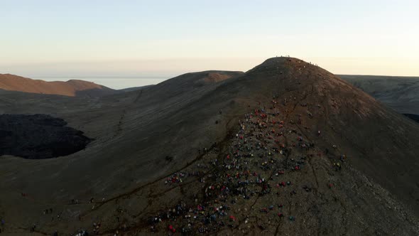 people sitting on a mountain watching a volcano alt