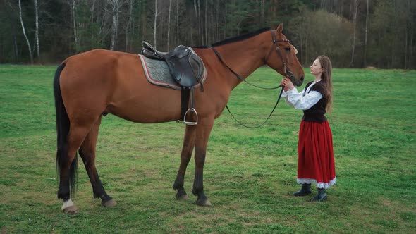Beautiful Female in a Medieval Dress Stands in a Field Next to a Horse  Slow Motion alt