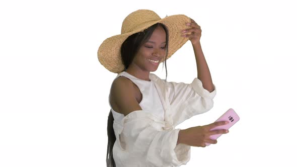 Smiling African American Woman in a Straw Hat Taking Selfie While Walking on White Background alt