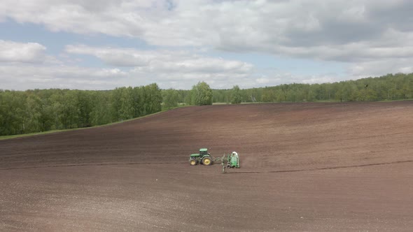 Tractor plows the ground with a plow in the field alt