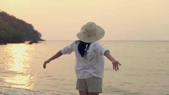 Young Asian woman traveler stretching with arms raised feeling to relax enjoy a holiday summer.