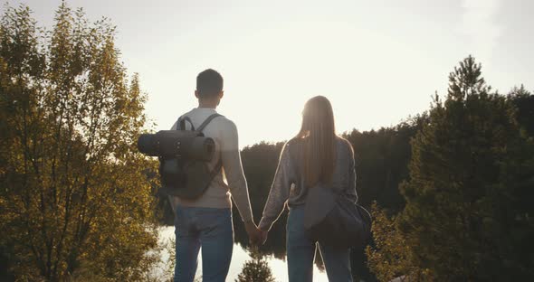 Male Female Travelers Standing on Hill Exploring Lake. Young Couple in Love Traveling Discover alt