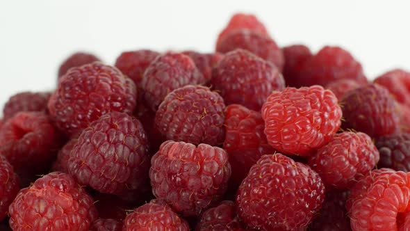 Beautiful ripe raspberry rotates on a plate. Slow rotation of raspberries close-up top view.