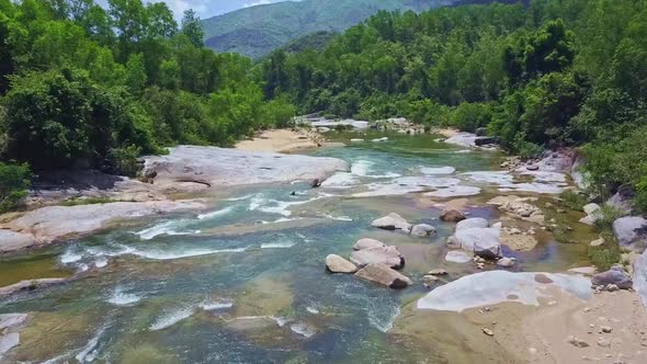 Drone Flies Closely To Mountain River with Rocky Banks alt
