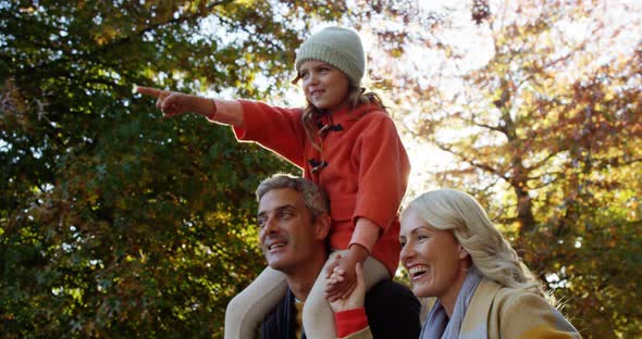 Girl on dads back with mom walking outdoors alt