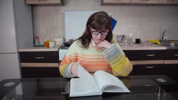 Woman Studying Business Literature in the Kitchen Turns Pages