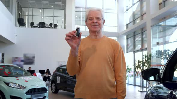 Senior Man Shows Car Key at the Dealership