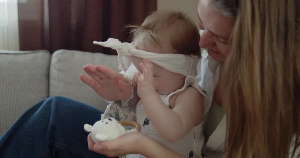 Mother Plays with Her Adorable Baby Daughter on a Sofa at Home