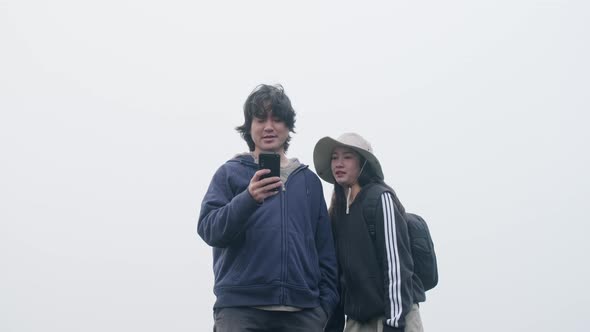 Couples of Asian tourists enjoy taking photos on top of the mountain with thick. alt