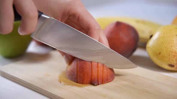 Women's Hands Cut a Juicy Peach with a Sharp Chef's Knife