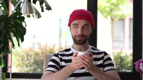 Handsome, young man enjoys coffee, he closes his eyes and takes a sip.