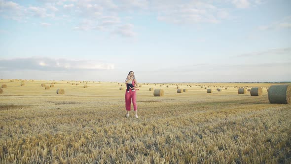 Beautiful Mother Walks and Has Joy with Lovely Little Baby Boy on Hands in Field alt