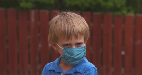 Portrait of a little boy unhappy to be wearing a protective face mask. alt
