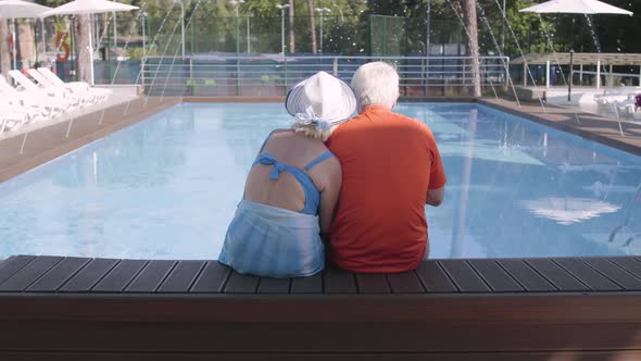 Happy Mature Couple Sitting on the Edge of the Pool alt