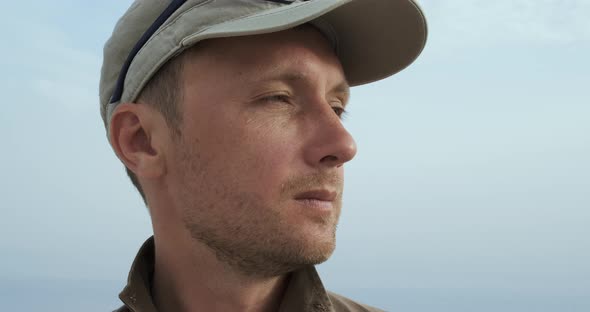Closeup Portrait of Handsome Bearded Man in Cap Against Blue Sky in Day Time alt