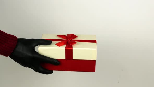 A man gives a woman a gift box in black COVID 19 gloves. Christmas shopping alt