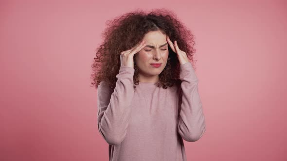 Young Beautiful Woman with Curly Hair Having Headache, Pink Studio Portrait alt