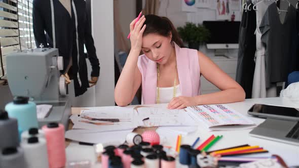 Beautiful tailor or designer woman sit on chair in workplace and feel bad with work