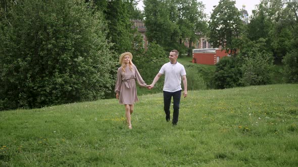 Man with a Woman Blonde in a Dress Walk on a Green Field in Nature in Summer alt