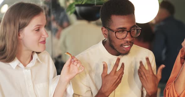 Close Up View of African American Guy Sharing Idea with Colleagues While They Eating in Cafe. Young alt