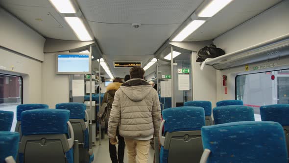 A Group of Adult Passengers Moves Along the Train Carriage Before Departure