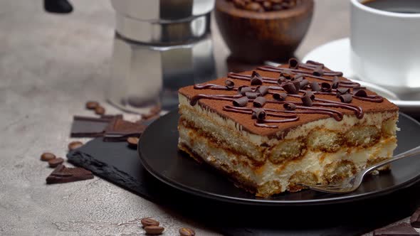 Portion of Traditional Italian Tiramisu dessert and mocha coffee maker on grey concrete background alt