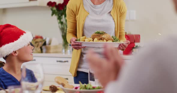 Caucasian woman in santa hat serving food to whole family alt