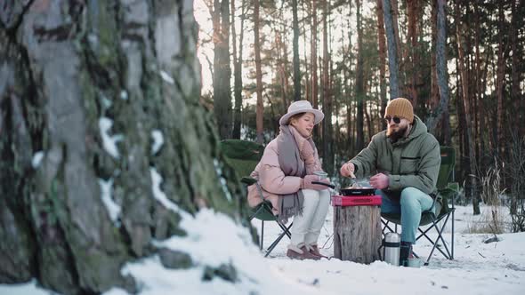 Couple Cooking Lunch at the Camp in the Woods on a Sunny Winter Day