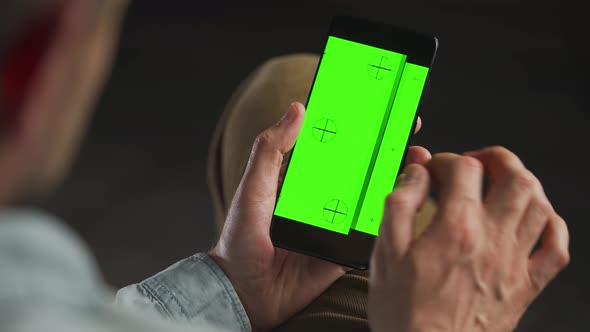 Man Using Smartphone with Green Mockup Screen in Vertical Mode alt