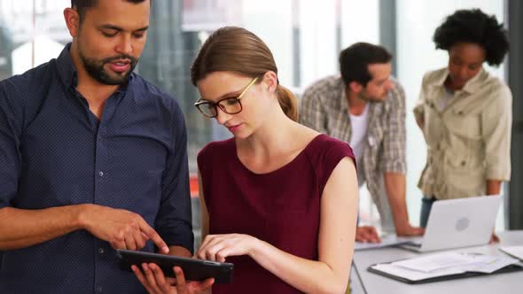 Business executives discussing over digital tablet alt