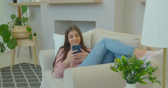 Happy Relaxed Young Woman Holding Smart Phone Looking at Cellphone Screen Using Mobile Apps for alt