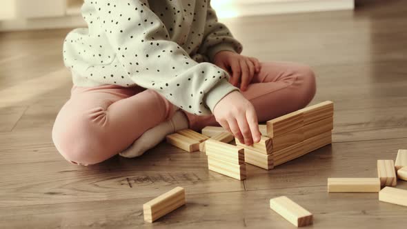 Little child plays a board game, kid builds from wooden bricks blocks. alt