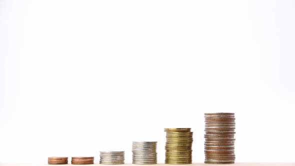 Closeup of human hand putting a coin on a pile of coins.