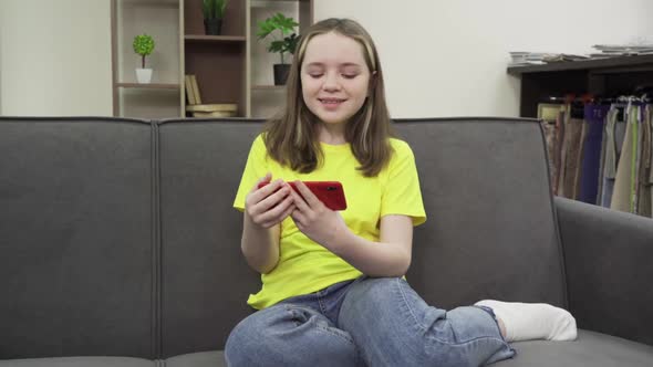 Happy Teenage Girl Watching a Video on Her Smartphone with a Smile alt
